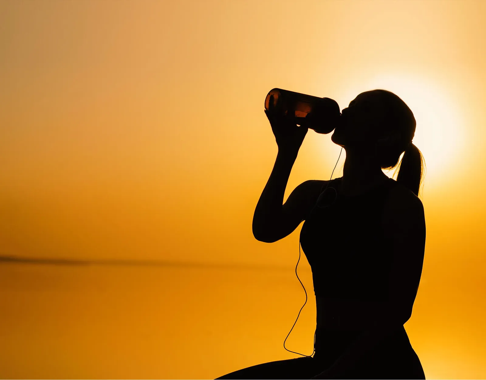 Atleta se hidratando ao pôr do sol